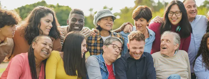 Groupe multigénérationnel et multiculturel riant ensemble en plein air, illustrant la diversité et le lien humain en thérapie